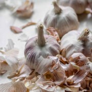 Heads of garlic surrounded by garlic peels with the text how to prep and freeze garlic.