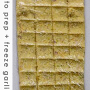 Minced garlic formed into a flat rectangle and sectioned into squares with the text how to prep + freeze garlic.