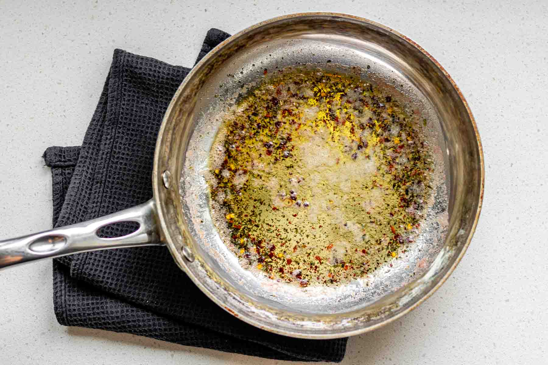 A skillet with melted butter and spices in it,