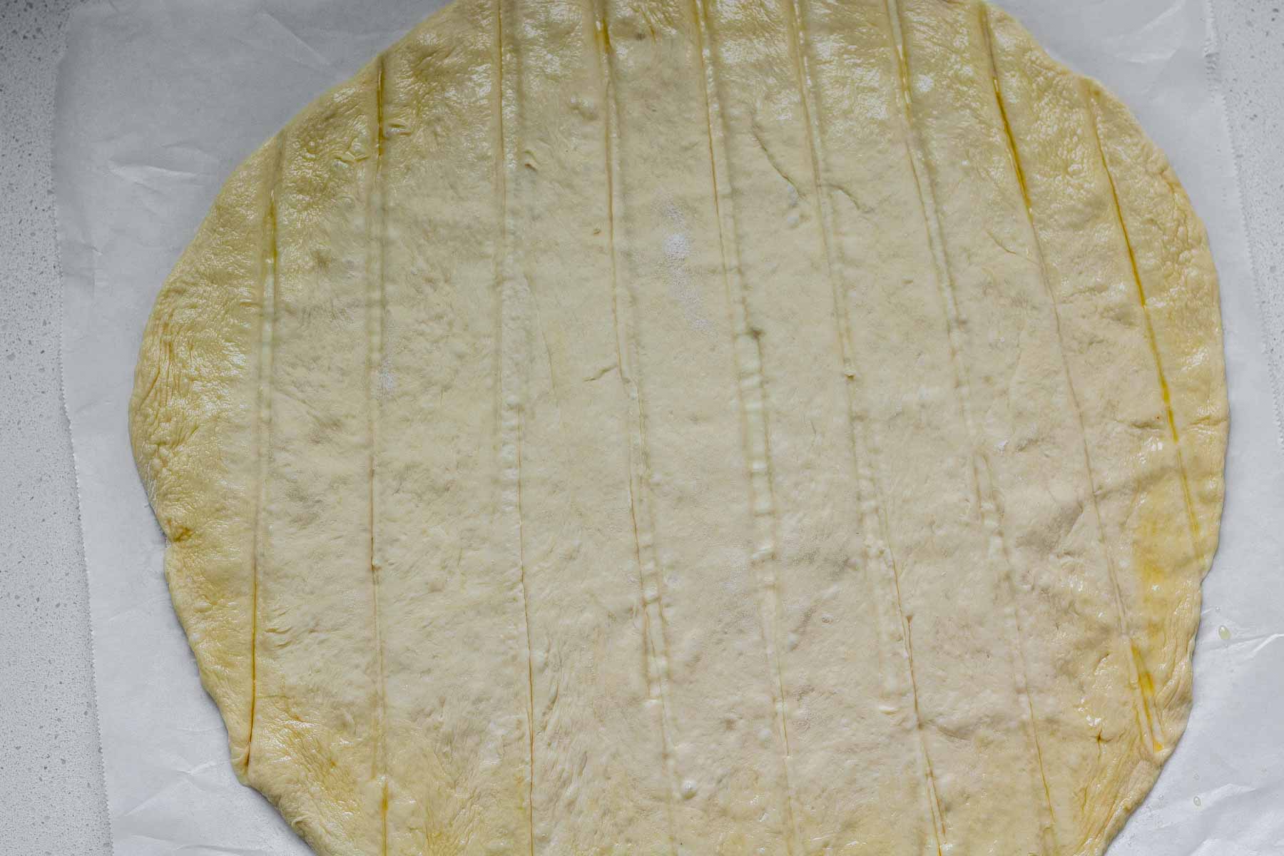 Uncooked flatbread dough with indented lines in it.