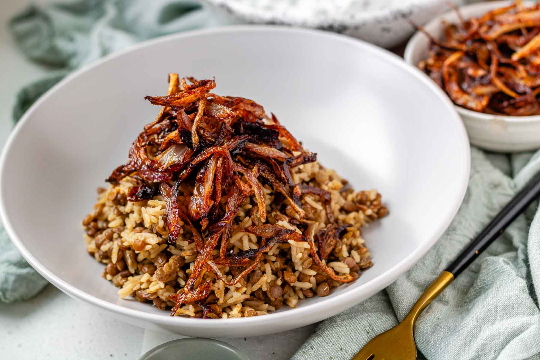 A bowl of rice and lentils, topped with crispy onions.