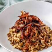 A bowl of rice and lentils, topped with crispy onions.