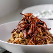 A bowl of rice and lentils, topped with crispy onions.