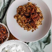 A bowl of rice and lentils, topped with crispy onions with the word mujaddara.