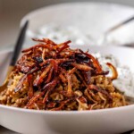 A bowl of rice and lentils, topped with crispy onions.