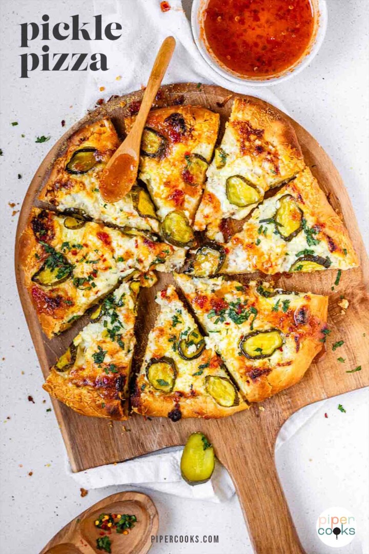 Pizza on a pizza peel topped with pickles and a red sauce with the text pickle pizza.