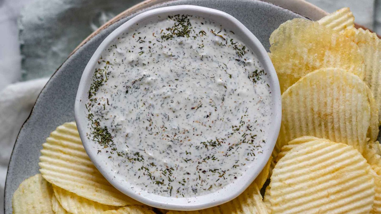 Dip in a bowl surrounded by potato chips.