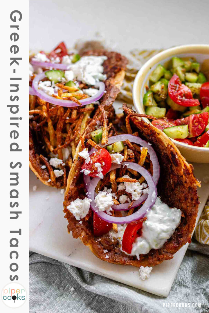 Tacos filled with meat, tomato, cucumber, red onion, feta, white sauce, and shoestring fries with the text Greek-Inspired Smash Tacos.