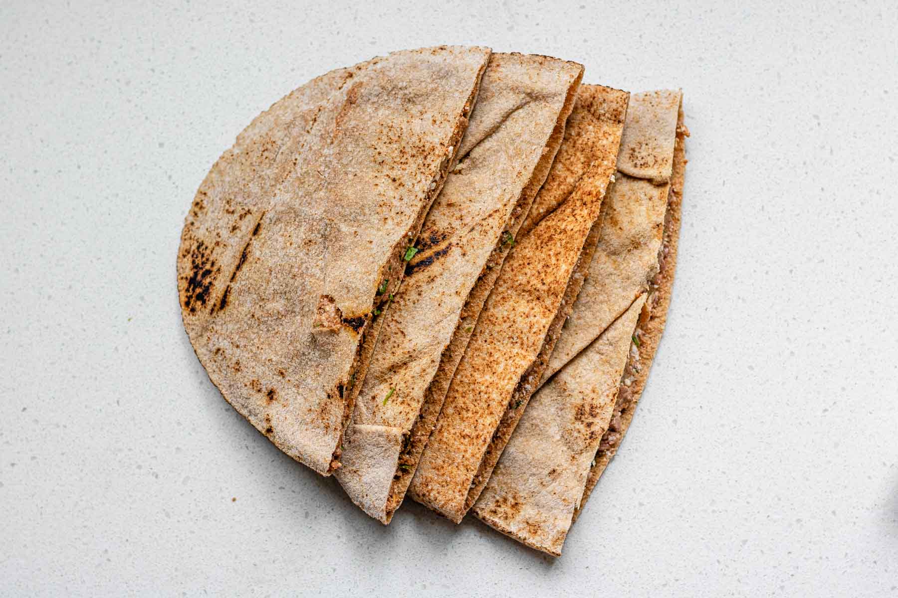 A stack of uncooked meat-filled pitas.
