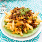 Fries topped with chili sauce, cheese, and greens.