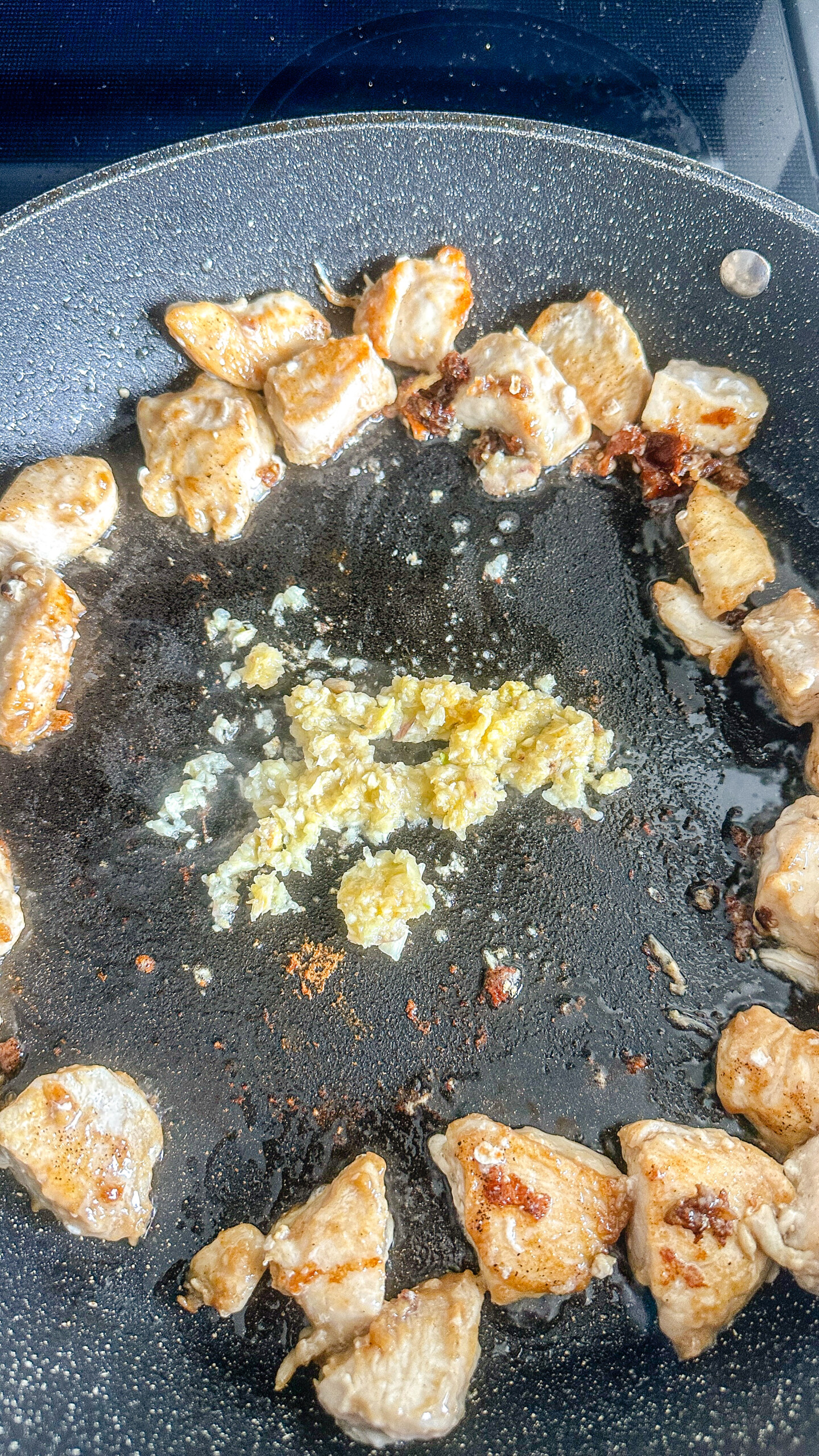 Cubed chicken with garlic in a skillet.