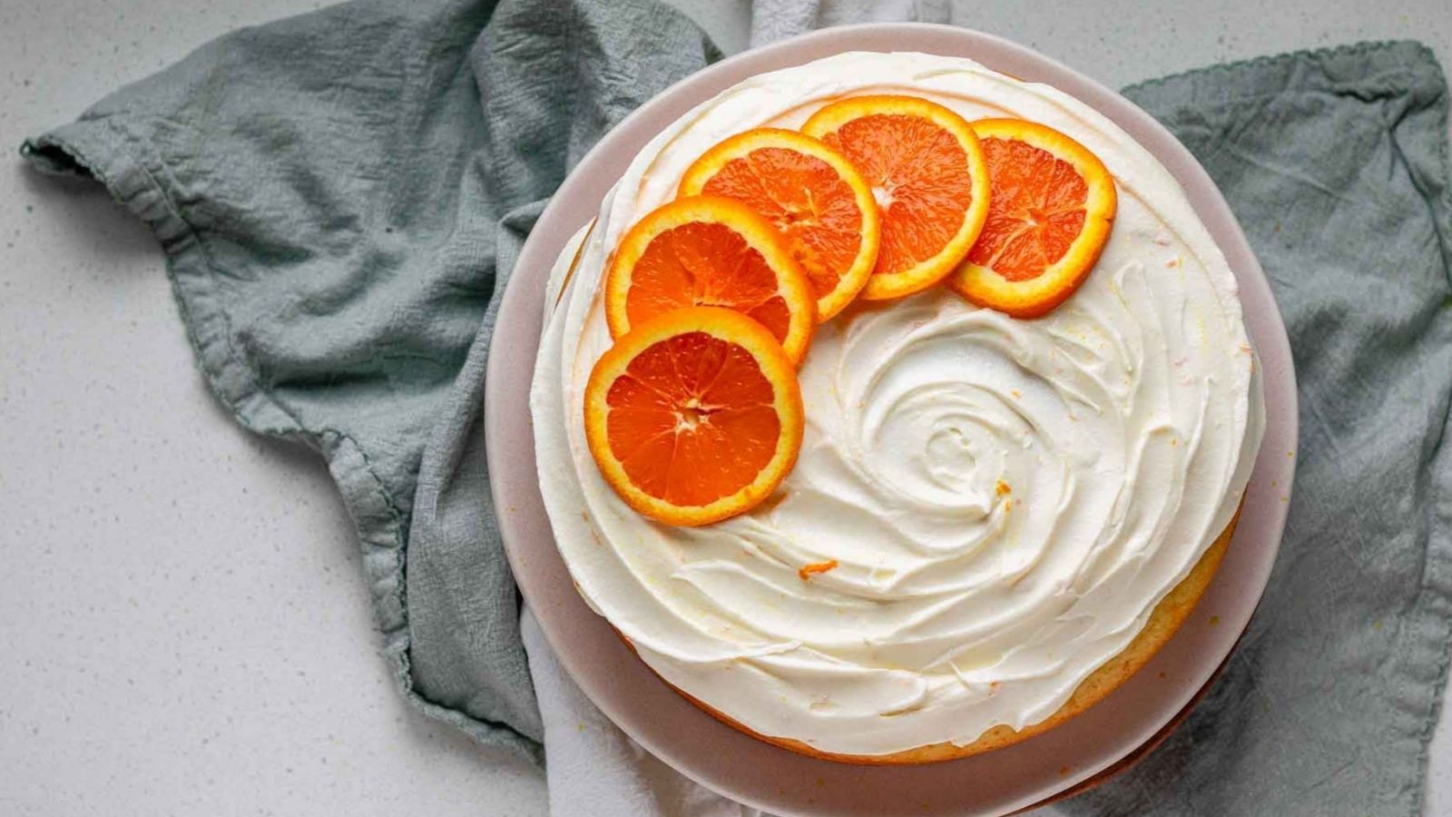 A cake with icing and orange slices on top.