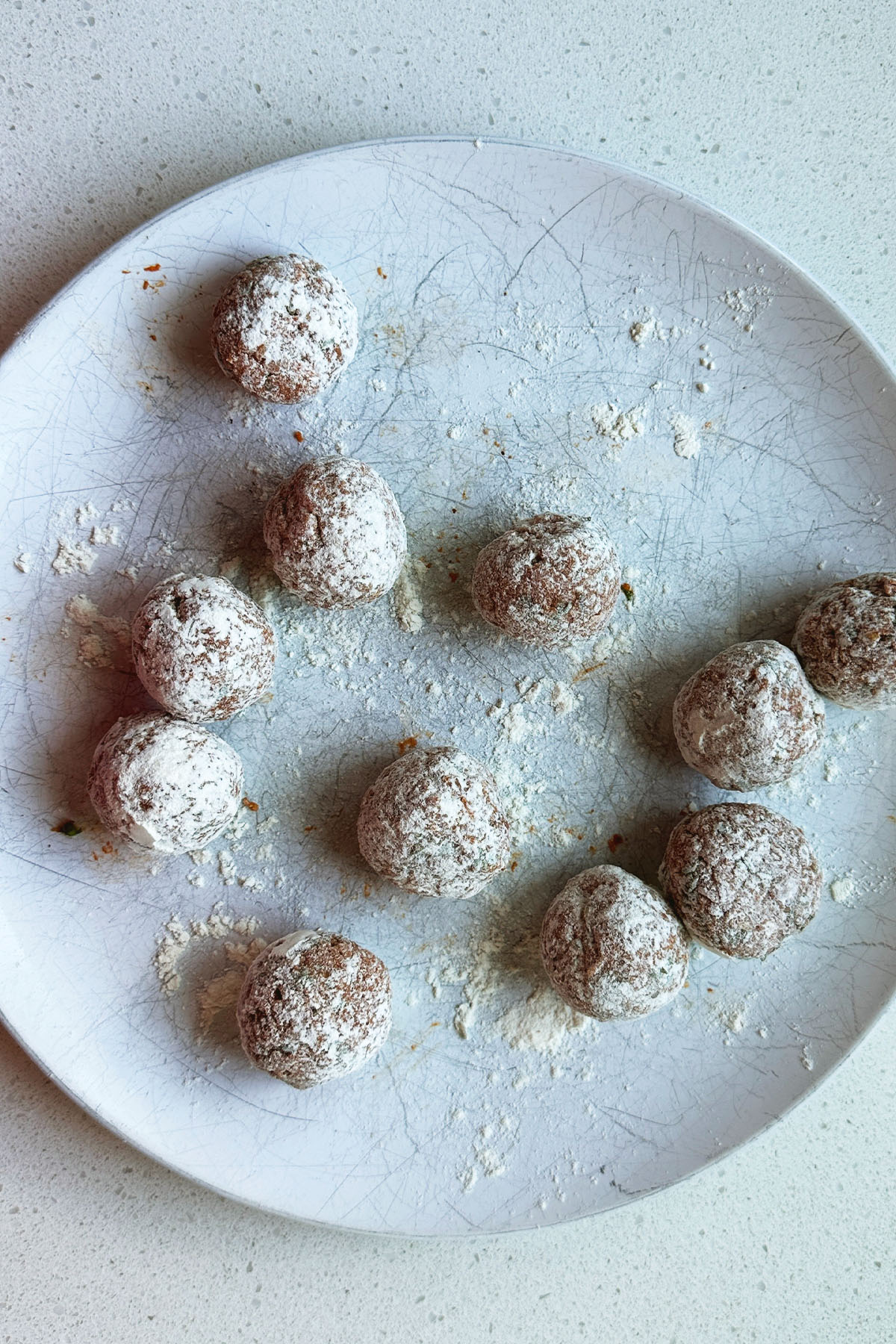 Meatballs coated in flour on a plate.