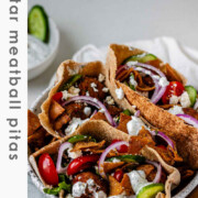 Pita stuffed with meatballs, tomato, cucumber, onion, tzatziki, and crispy pita bits with the text za'atar meatball pitas.