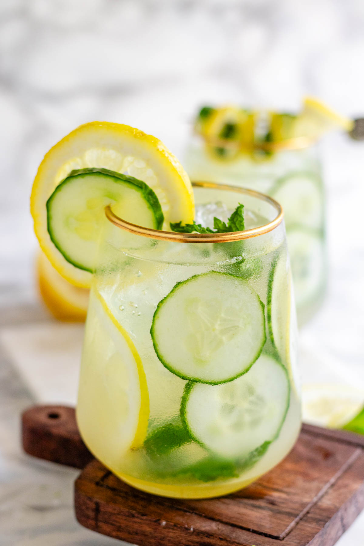 A cocktail garnished with lemon and cucumber slices and fresh mint.