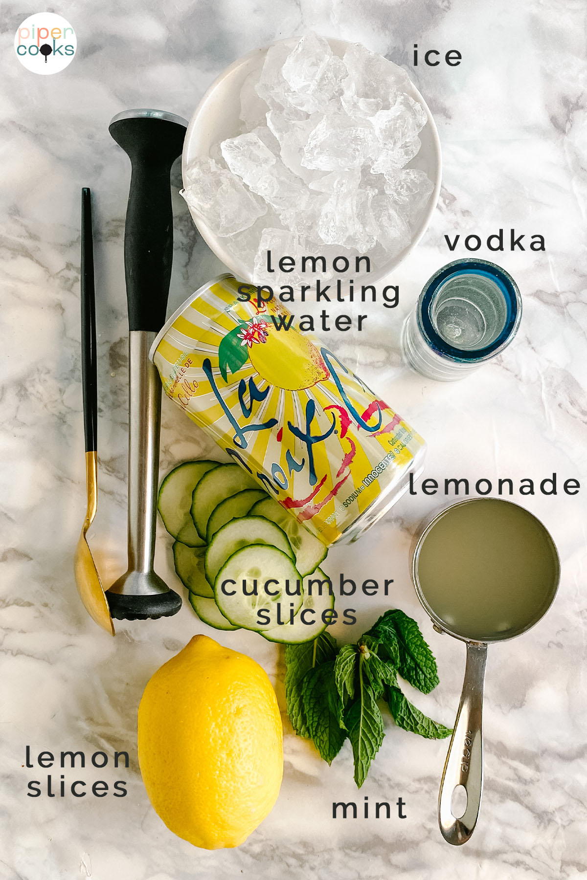 Ingredients for a lemon cucumber mint vodka cocktail on a white marble counter, labeled.
