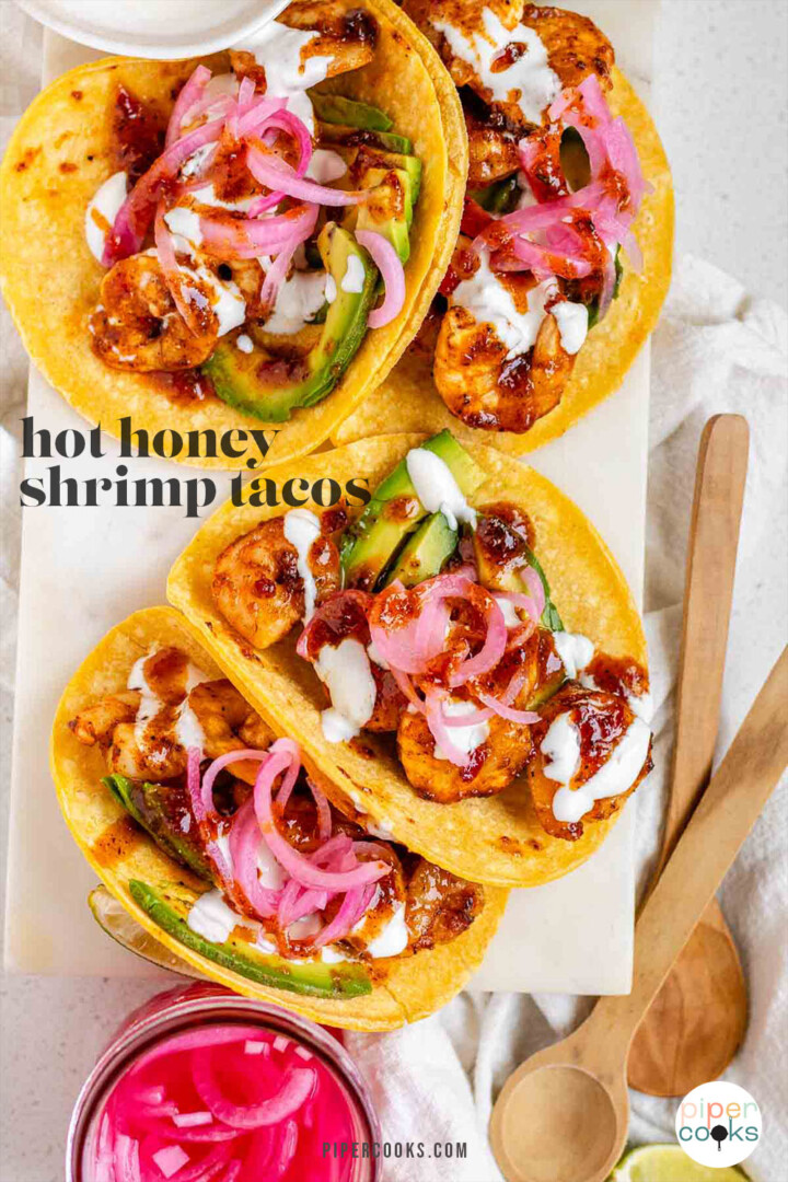 Hot honey Cajun shrimp tacos on a white platter with garlic lime crema and pickled onions with the text hot honey shrimp tacos.