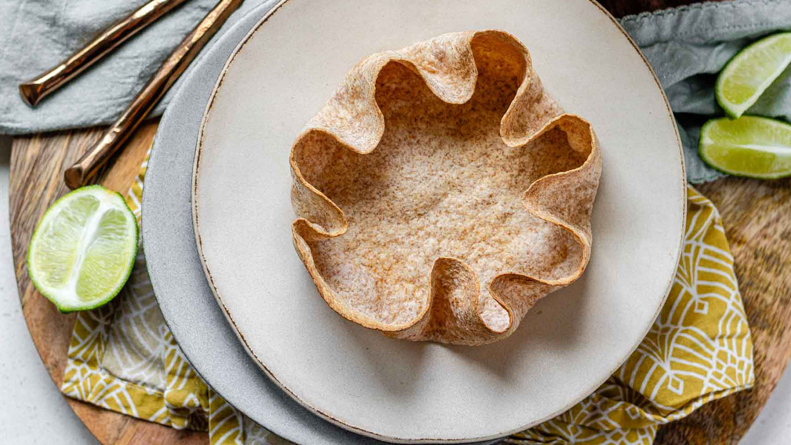 A whole wheat tortilla salad bowl on a plate with the text taco salad tortilla bowls.