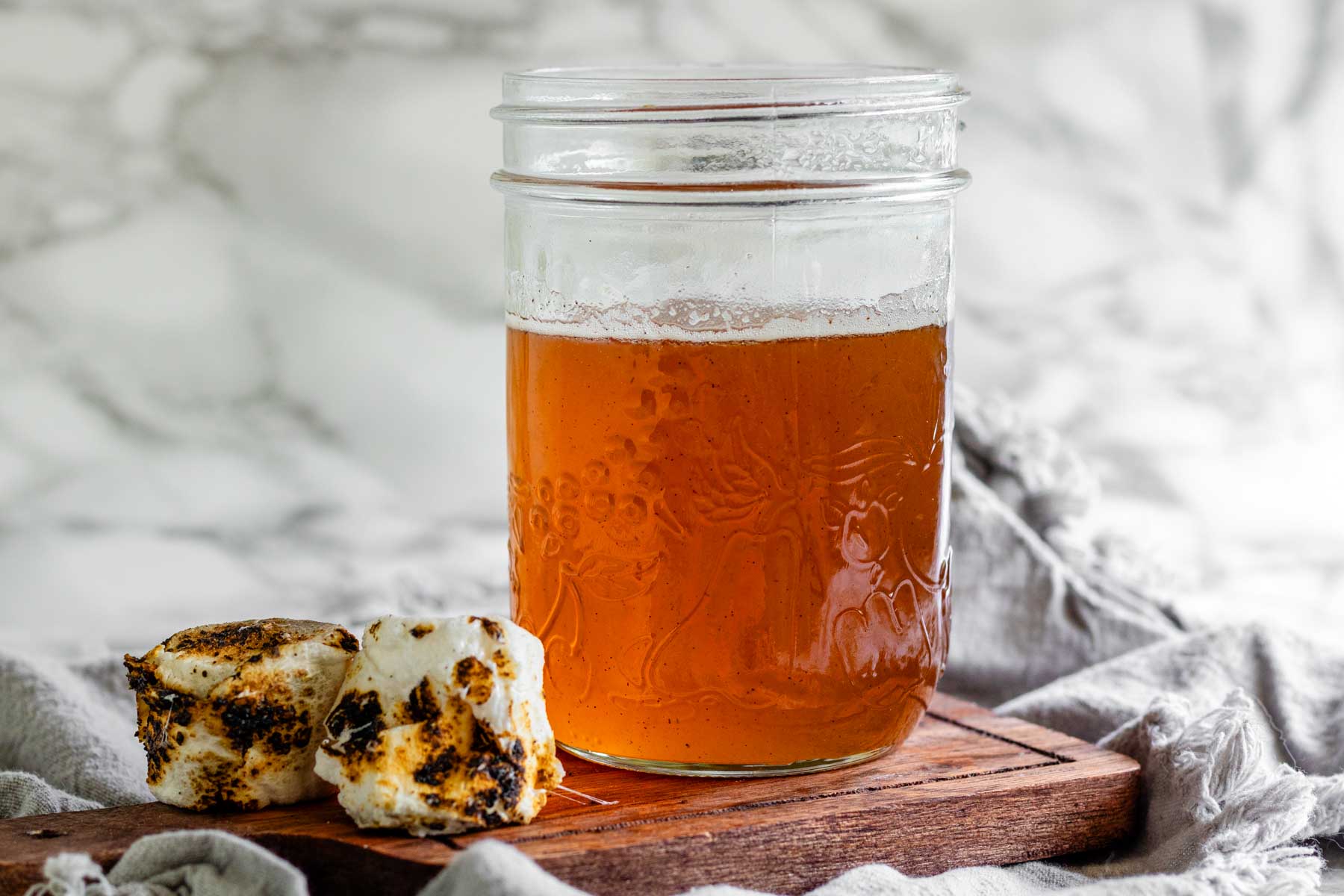 Toasted marshmallow syrup in a glass jar with toasted marshmallows.