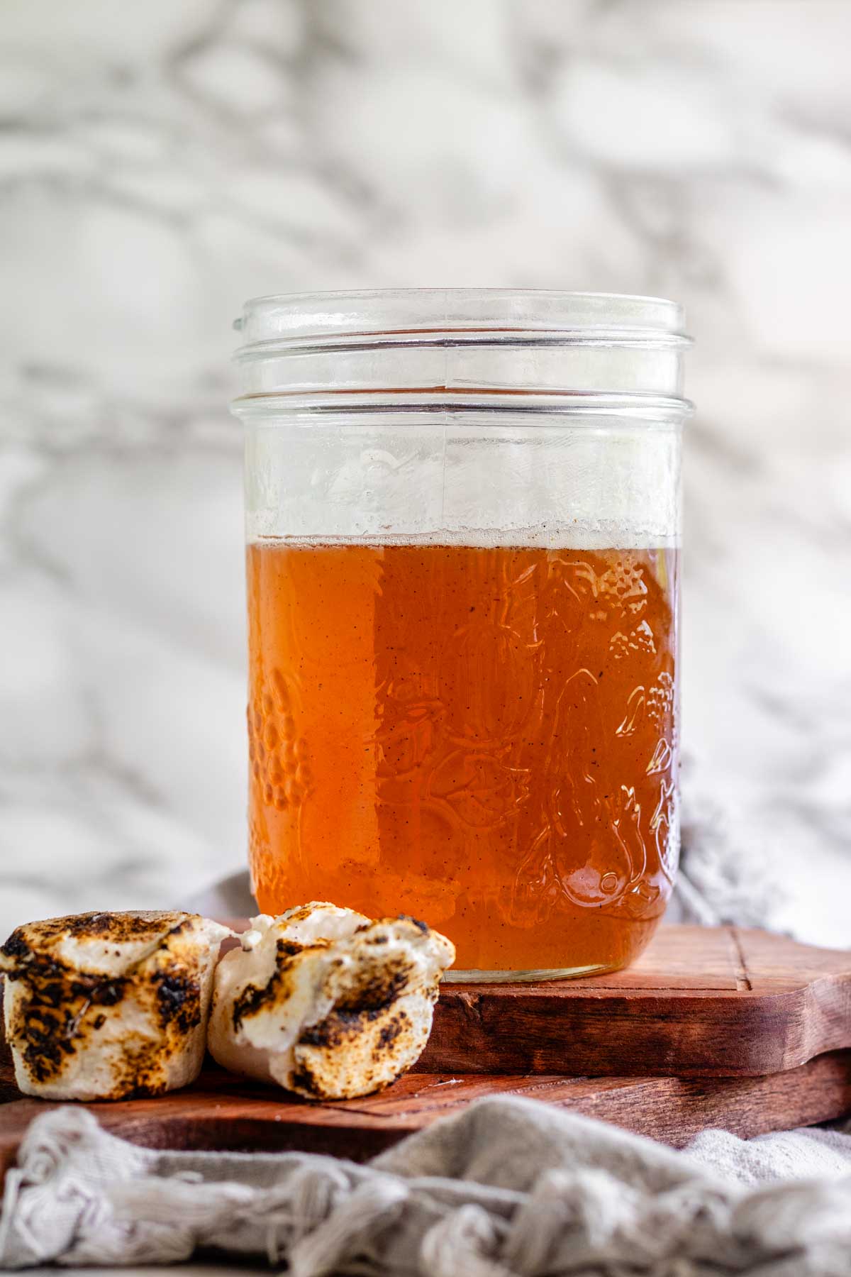 Toasted marshmallow syrup in a glass jar with toasted marshmallows.