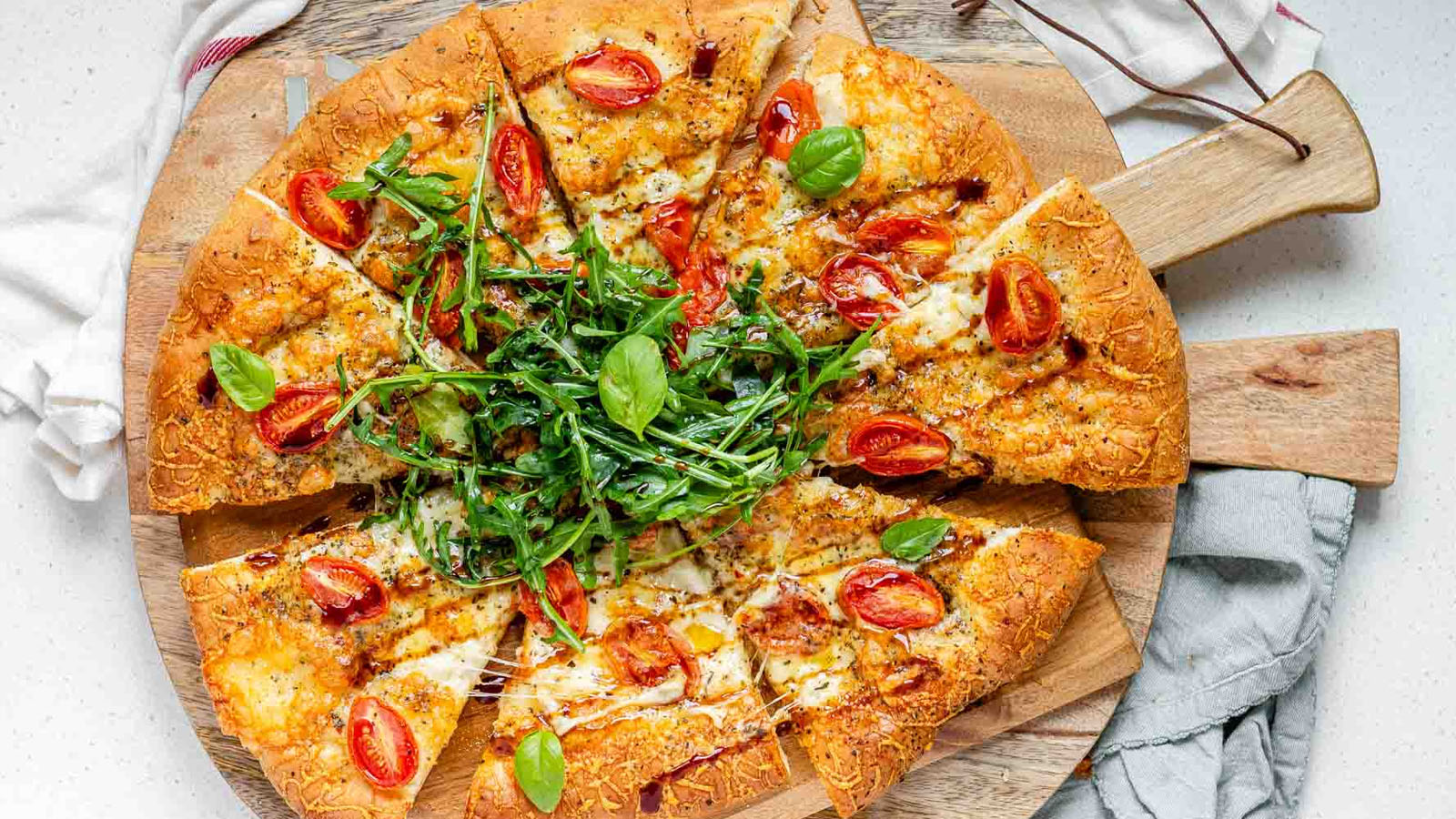Pizza topped with arugula and basil leaves.