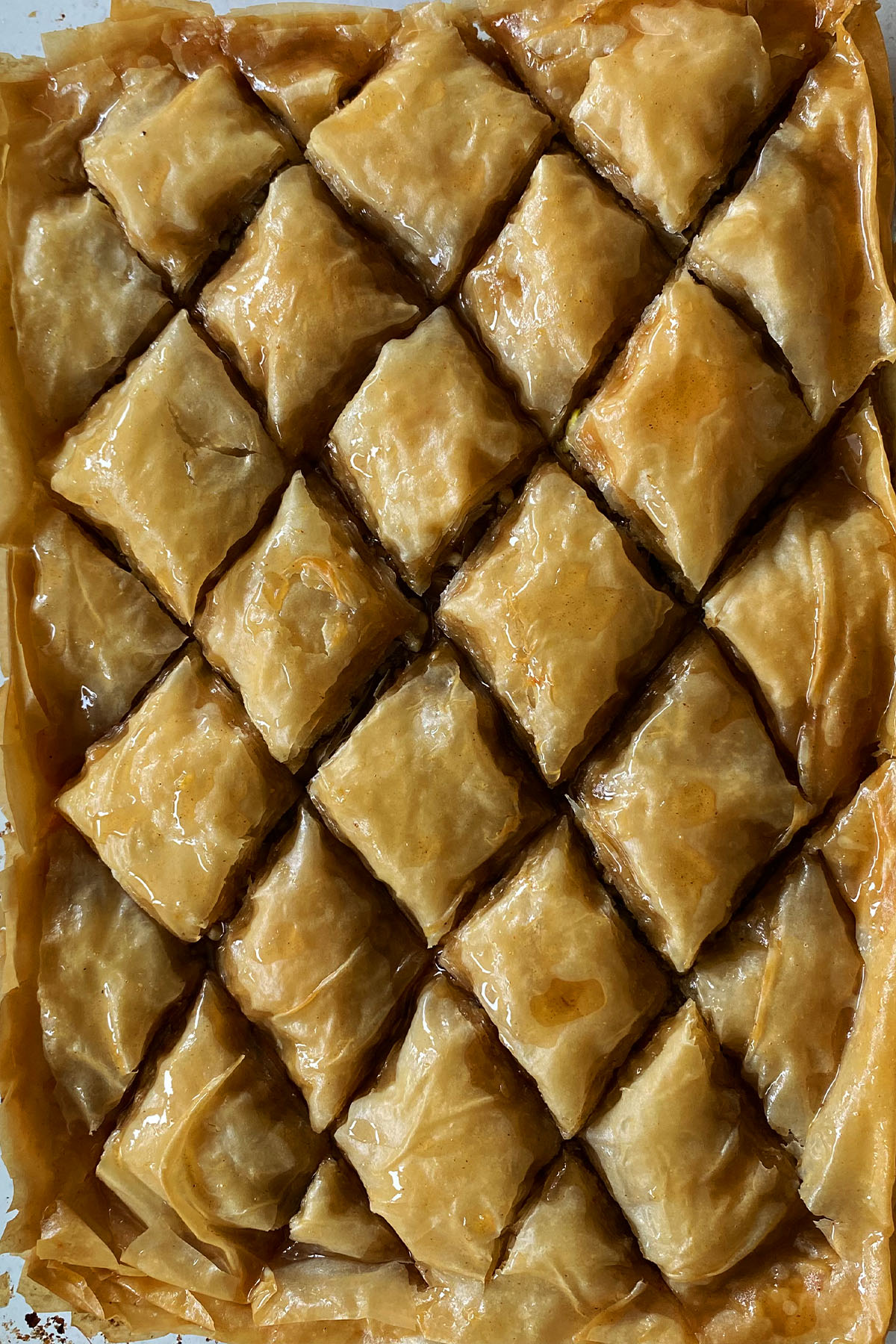 Baked baklava cut into diamond shapes, covered in syrup.