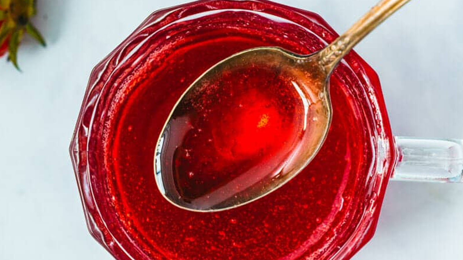 Red syrup in a jar with a spoon.