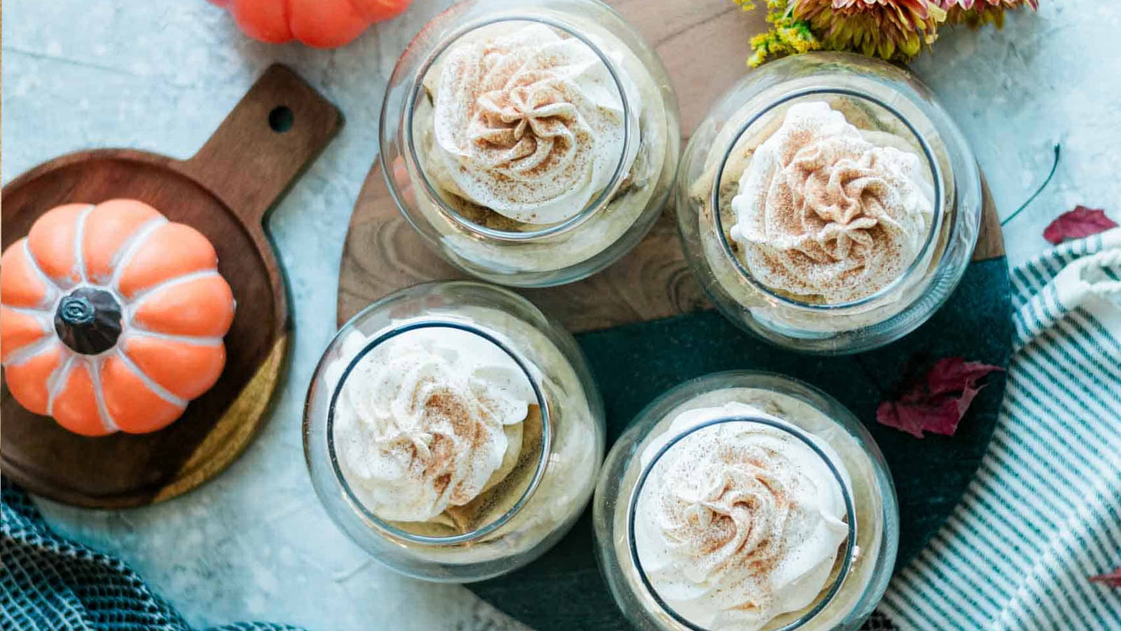 Desserts in cups topped with a swirl of whipped cream and cinnamon.