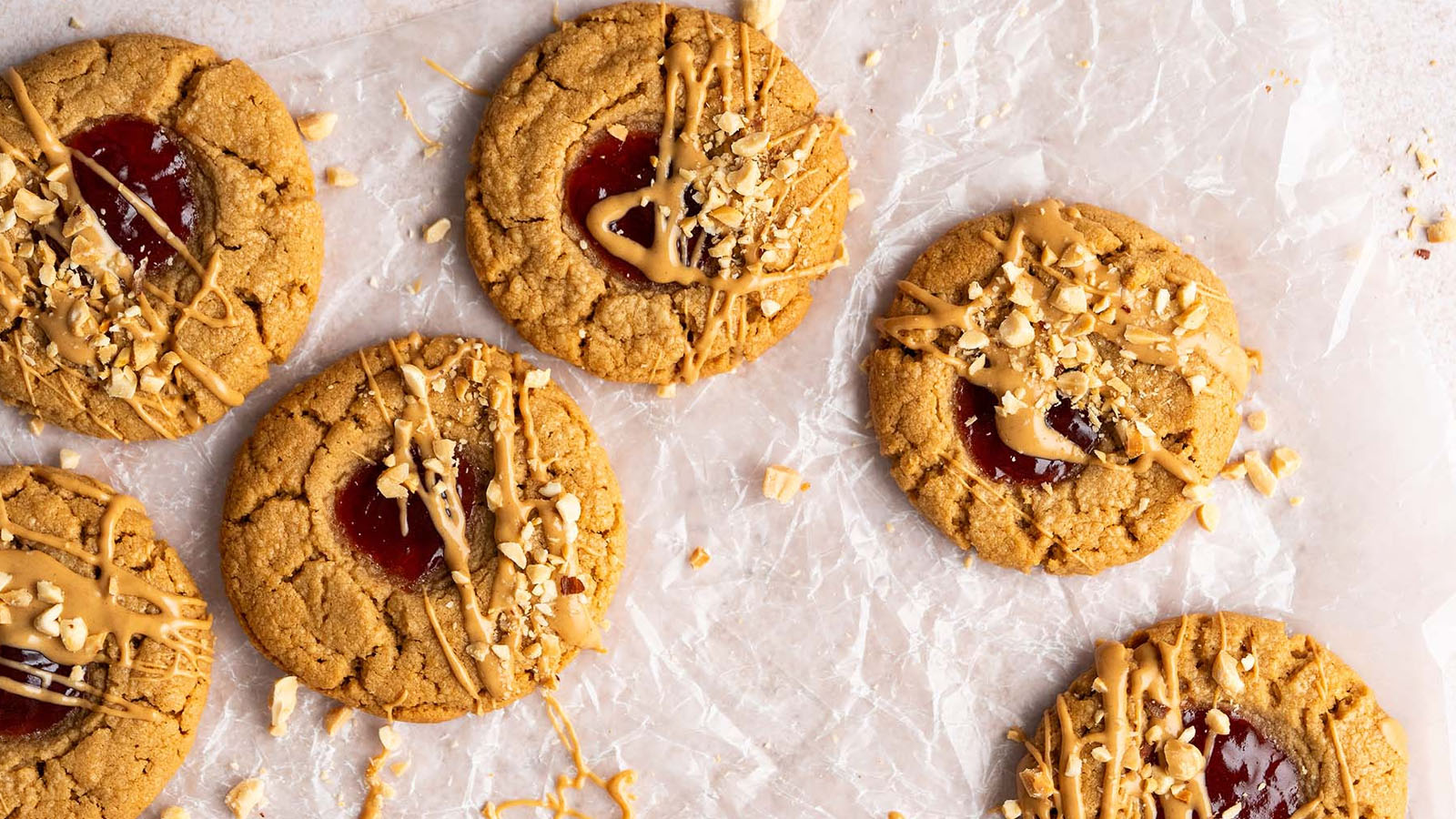 Cookies topped with jam, chopped peanuts, and peanut butter drizzle.
