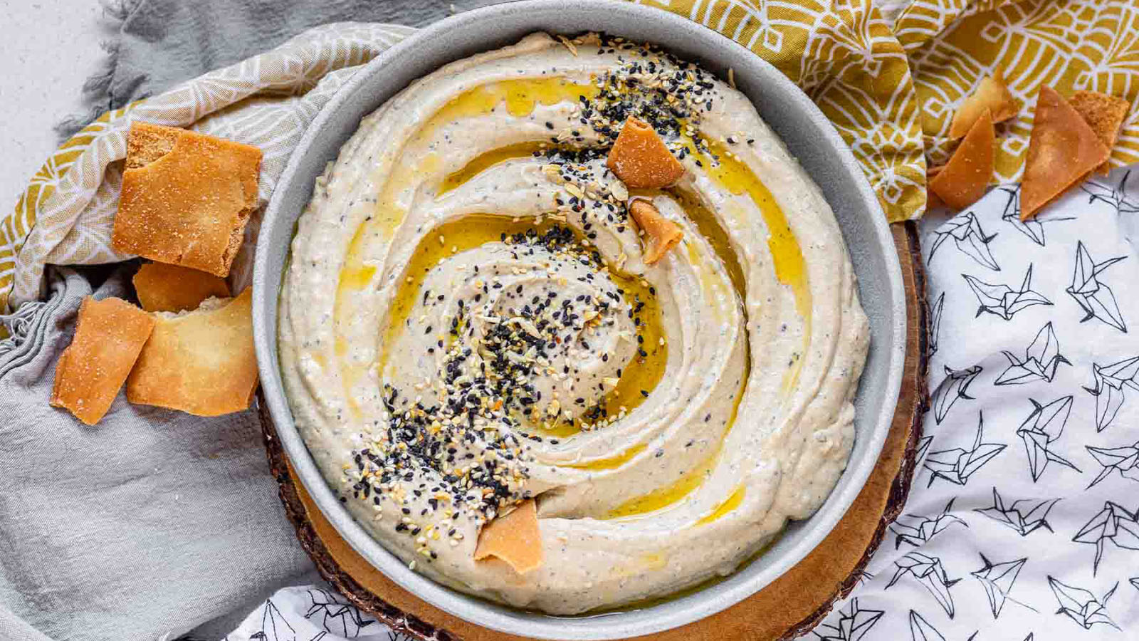 Hummus in a bowl topped with olive oil and a seed mix.