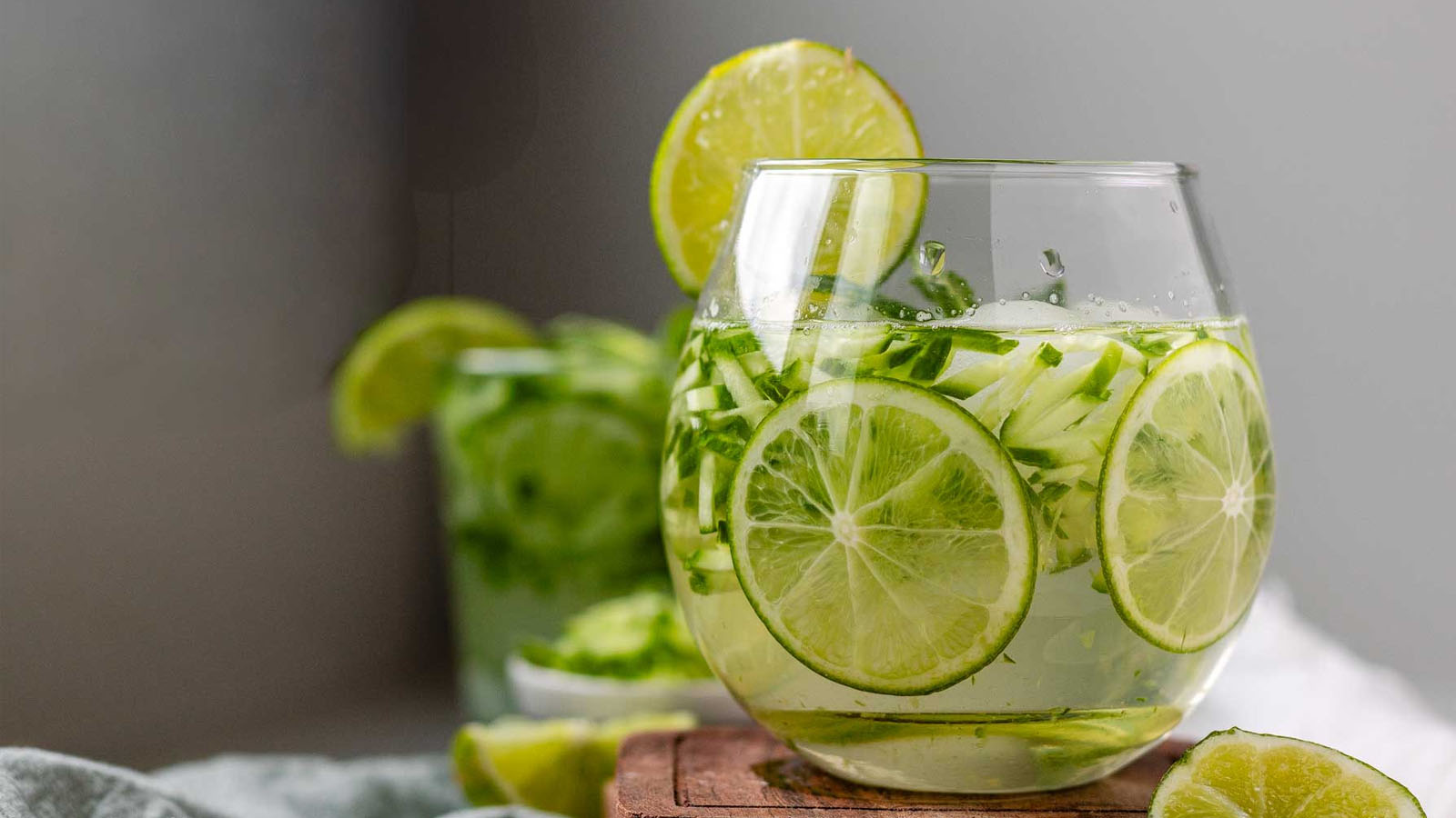 A cocktail with cucumber and lime garnishes.